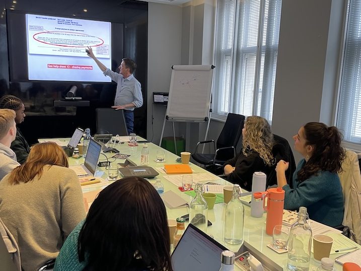 David in front of a screen, showing a group of young freelancers how to chase late payments when you invoice.