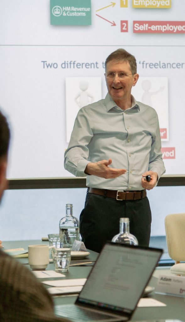 David standing in front of a screen which says 'employed' 'self-employed'. Trainees look on.