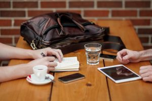 business meeting in coffee shop with notebook and iPad on the table alongside drinks